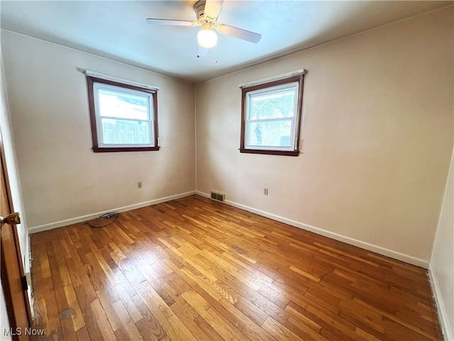 unfurnished room featuring ceiling fan, a wealth of natural light, and hardwood / wood-style floors