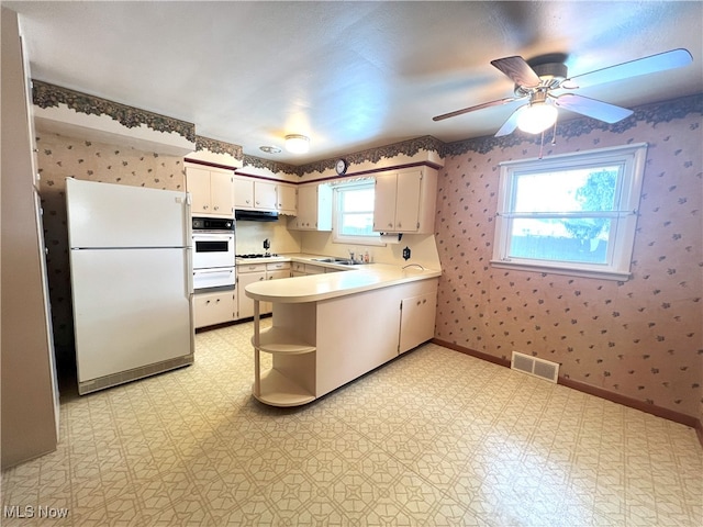 kitchen with sink, white appliances, white cabinets, and kitchen peninsula