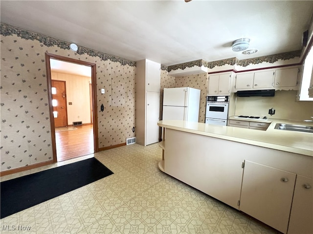 kitchen featuring sink, white appliances, and white cabinetry