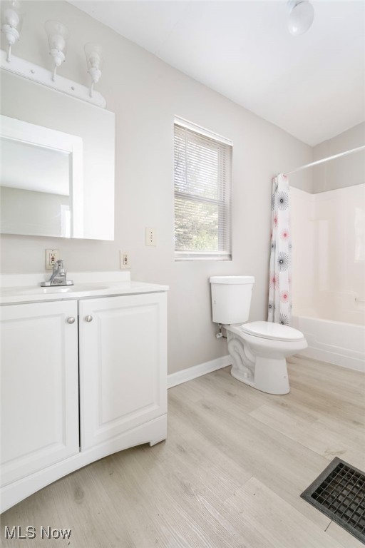 full bathroom with wood-type flooring, toilet, vanity, and shower / tub combo with curtain