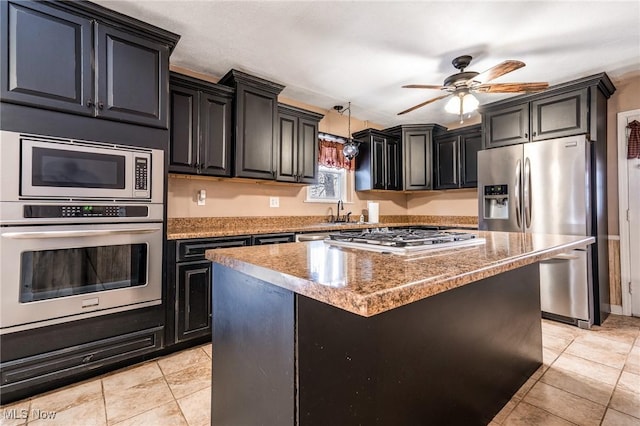 kitchen with a kitchen island, stainless steel appliances, sink, stone countertops, and light tile patterned floors