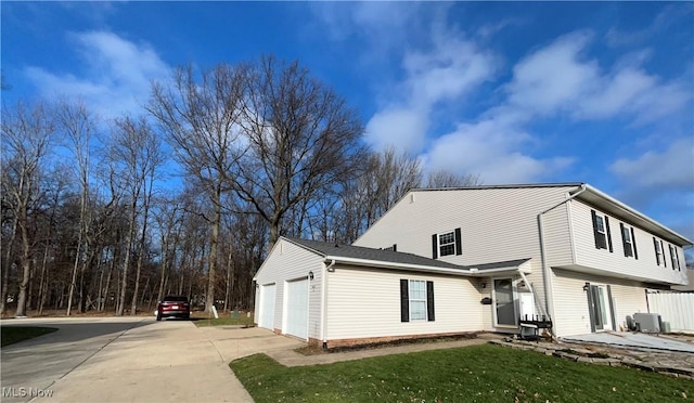 view of property exterior with central air condition unit, a lawn, and a garage