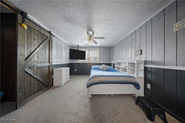 bedroom with ceiling fan, a textured ceiling, light carpet, and wood walls