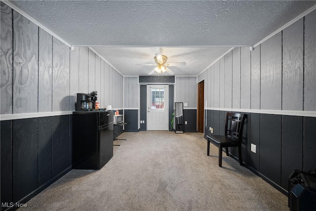 home office with light carpet, ceiling fan, crown molding, and a textured ceiling