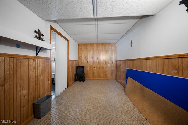 interior space with a paneled ceiling and wooden walls