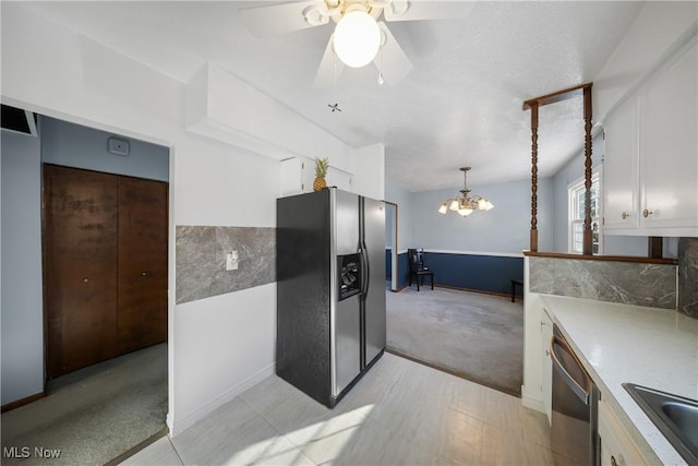 kitchen with pendant lighting, white cabinetry, stainless steel appliances, light carpet, and a textured ceiling