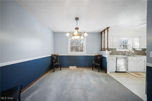 unfurnished dining area with sink, a textured ceiling, and an inviting chandelier