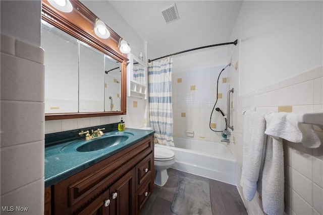 full bathroom with tile walls, shower / bath combination with curtain, hardwood / wood-style flooring, vanity, and toilet