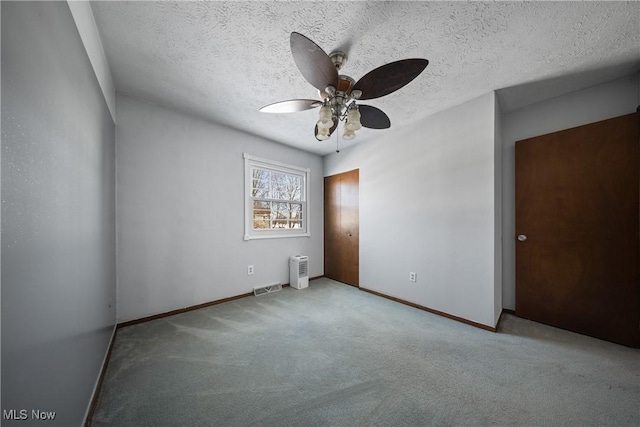 carpeted spare room featuring ceiling fan and a textured ceiling