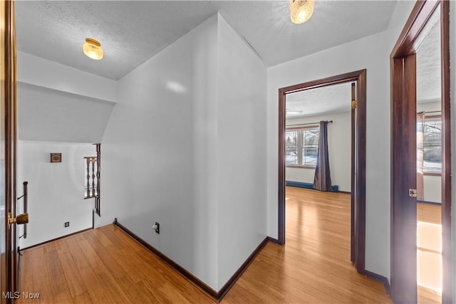 hall featuring light wood-type flooring and a textured ceiling