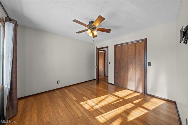 unfurnished bedroom with light wood-type flooring, a textured ceiling, a closet, and ceiling fan