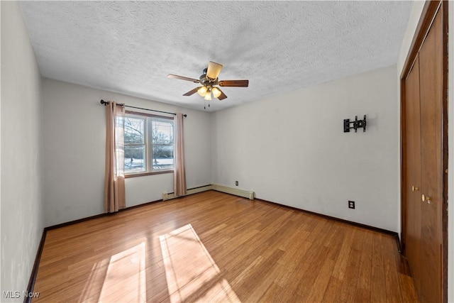 spare room with light hardwood / wood-style floors, a textured ceiling, a baseboard heating unit, and ceiling fan