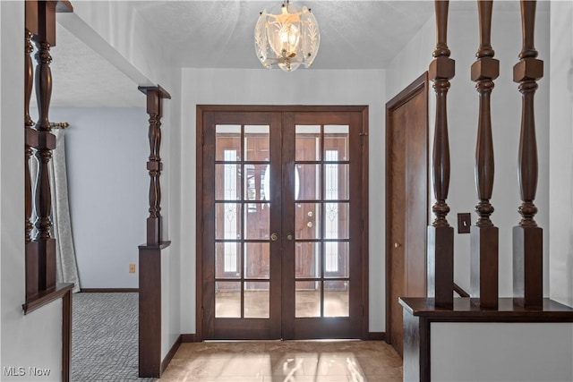 doorway to outside featuring light carpet, a textured ceiling, a notable chandelier, and french doors