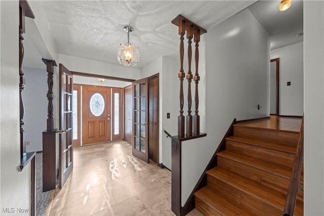 entryway with an inviting chandelier and a textured ceiling