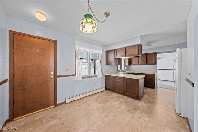 kitchen with pendant lighting, white refrigerator, a baseboard radiator, and sink