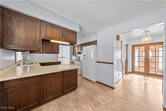 kitchen featuring kitchen peninsula, french doors, sink, decorative light fixtures, and white appliances