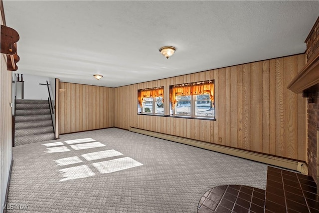 spare room featuring wooden walls, baseboard heating, and light carpet