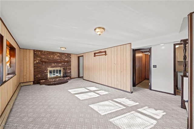 unfurnished living room featuring light colored carpet, wooden walls, a fireplace, and a baseboard heating unit