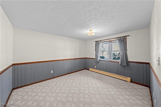 carpeted empty room with a textured ceiling and a baseboard heating unit