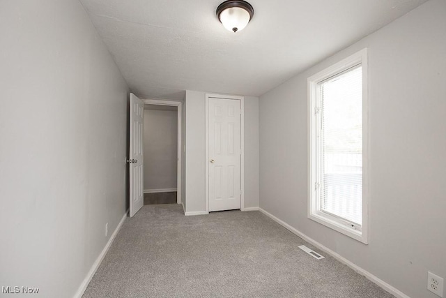 unfurnished bedroom with multiple windows, light colored carpet, and a closet