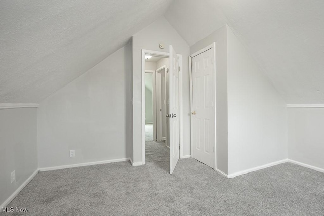 bonus room with light carpet, a textured ceiling, and lofted ceiling