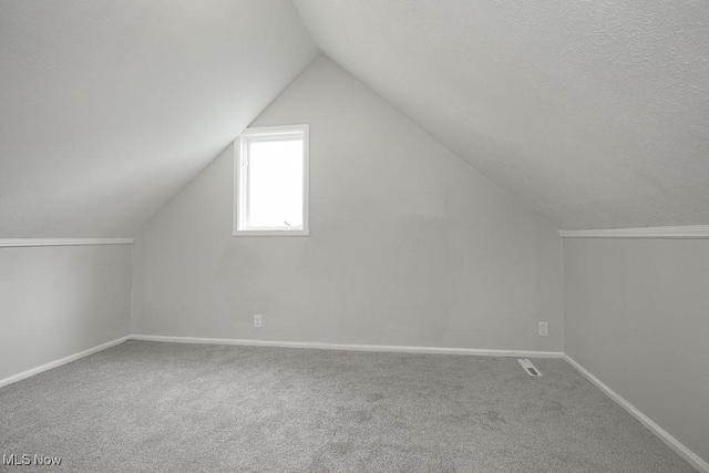 bonus room featuring carpet flooring, a textured ceiling, and lofted ceiling