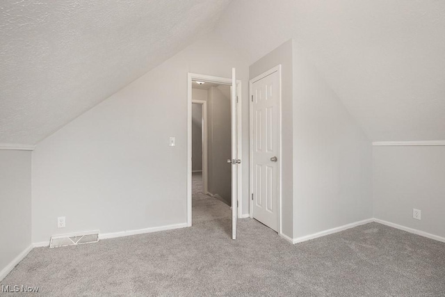 additional living space with carpet, a textured ceiling, and lofted ceiling