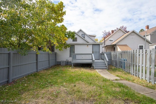 rear view of house with a deck, central AC unit, and a yard