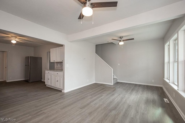 unfurnished living room featuring ceiling fan, beamed ceiling, and hardwood / wood-style floors