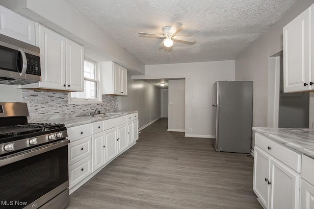 kitchen featuring white cabinets, light stone counters, appliances with stainless steel finishes, and sink