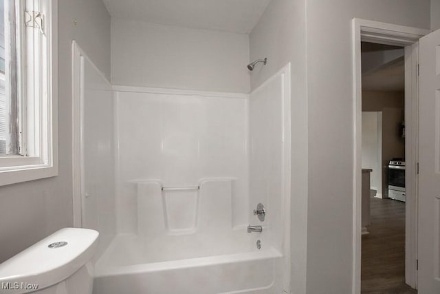 bathroom featuring tub / shower combination, wood-type flooring, and toilet