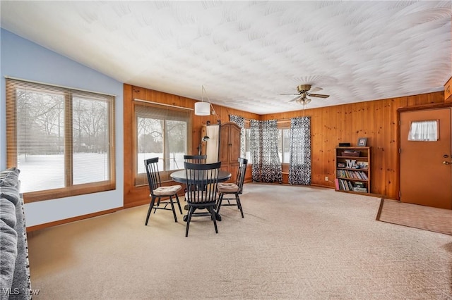 carpeted dining space featuring wooden walls