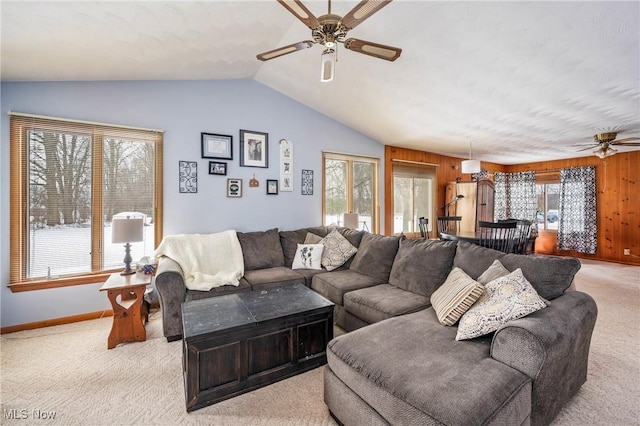 carpeted living room with ceiling fan, lofted ceiling, and wooden walls