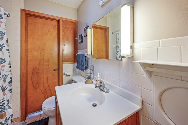 bathroom with tile patterned floors, vanity, toilet, and tile walls