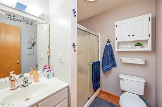 bathroom featuring hardwood / wood-style flooring, vanity, an enclosed shower, and toilet