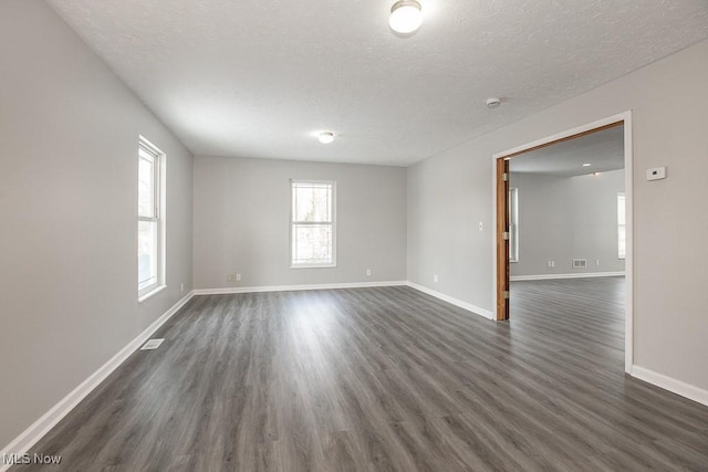 unfurnished room with dark wood-type flooring and a textured ceiling