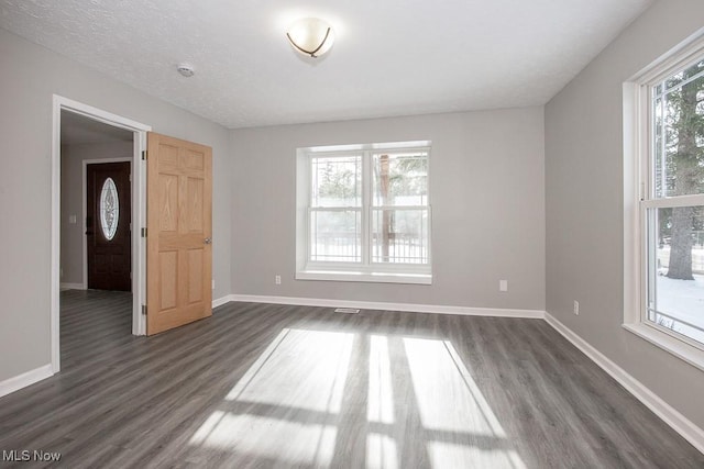 spare room featuring dark hardwood / wood-style floors and a textured ceiling