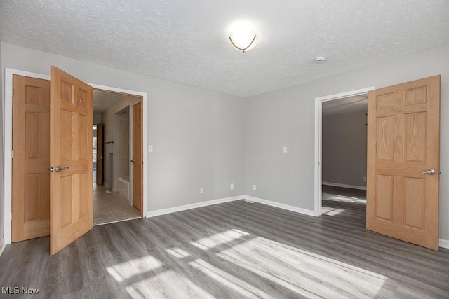 unfurnished room with hardwood / wood-style flooring and a textured ceiling