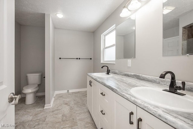 bathroom with a textured ceiling, toilet, and vanity