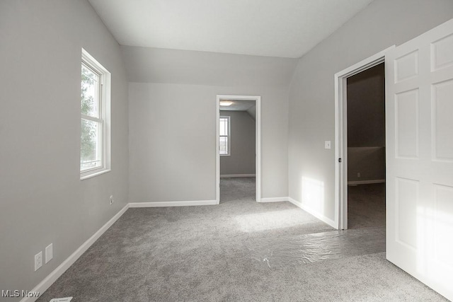 carpeted empty room with lofted ceiling