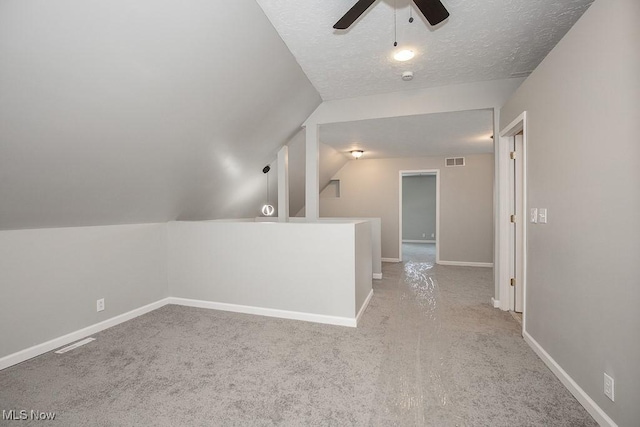 bonus room featuring light colored carpet, a textured ceiling, vaulted ceiling, and ceiling fan