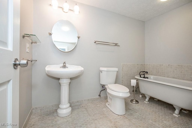 bathroom with a tub, a textured ceiling, and toilet