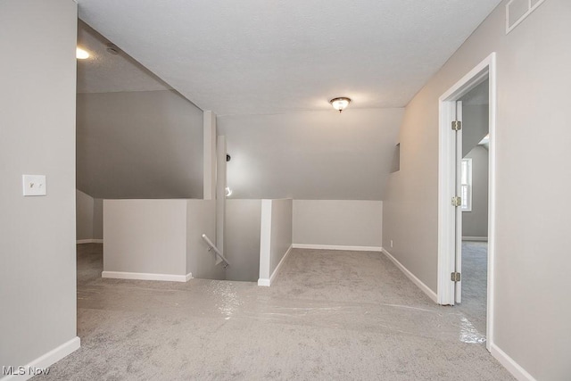 additional living space with a textured ceiling and lofted ceiling