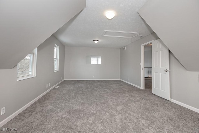 bonus room featuring vaulted ceiling, carpet flooring, and a textured ceiling