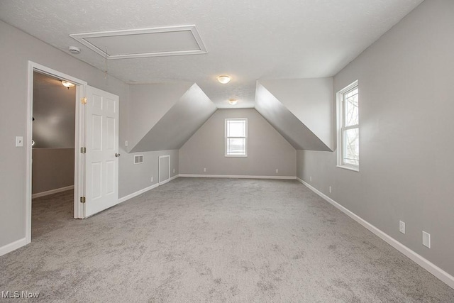 bonus room with light colored carpet, a textured ceiling, and lofted ceiling