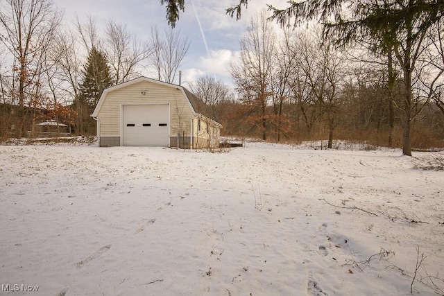 yard layered in snow with a garage and an outbuilding