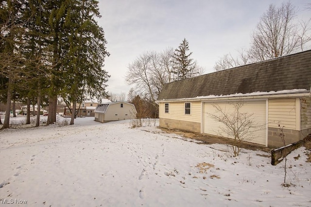 view of snowy exterior featuring a garage and an outdoor structure