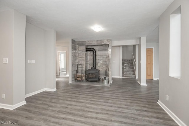 unfurnished living room with dark wood-type flooring and a wood stove