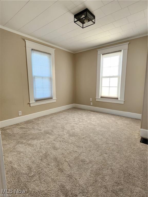 unfurnished room featuring carpet and crown molding