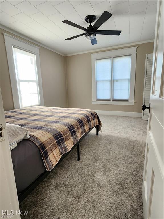 carpeted bedroom featuring crown molding and ceiling fan